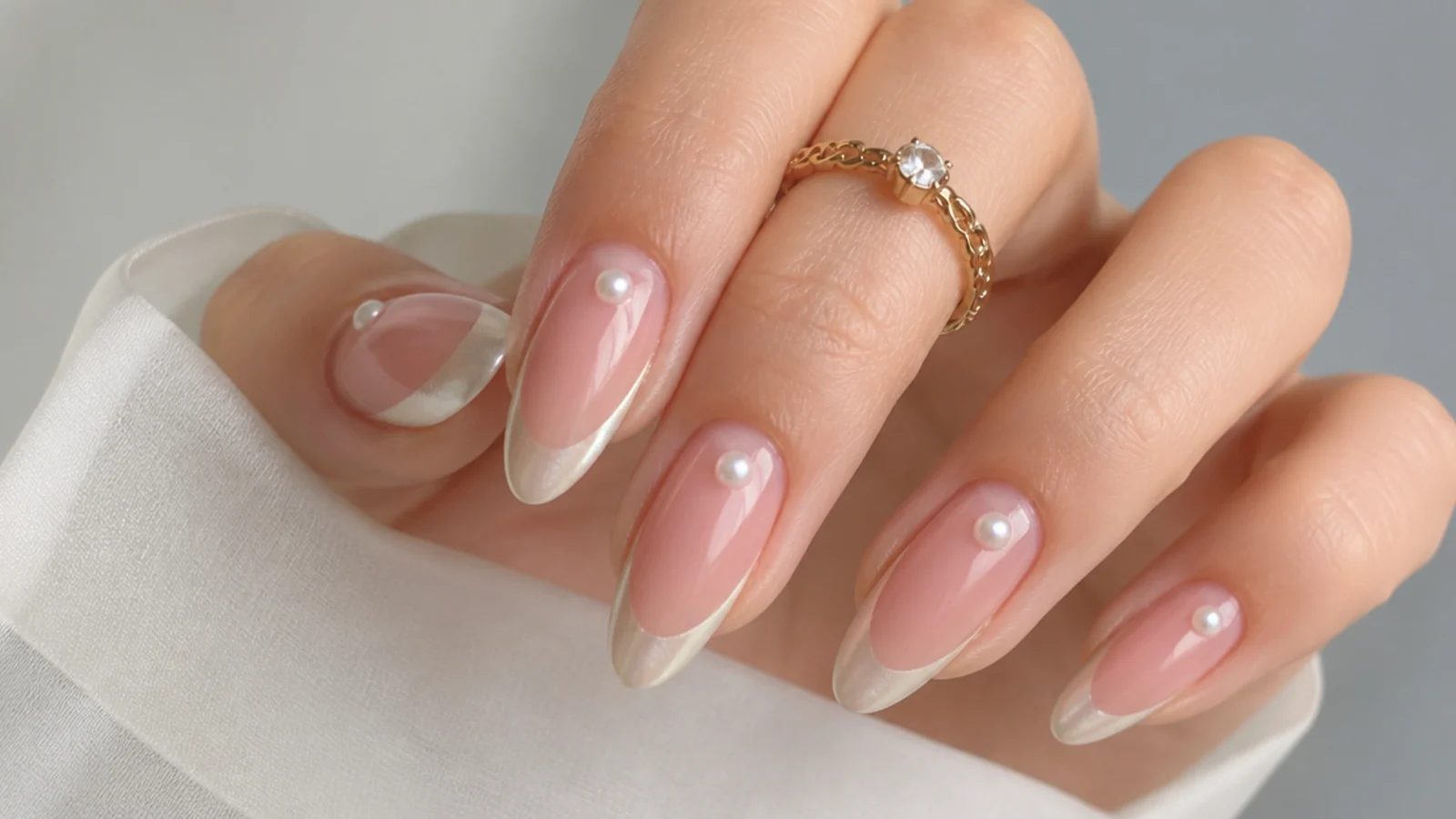 Almond nails with a pearl chrome french tip and a tiny pearl half-moon