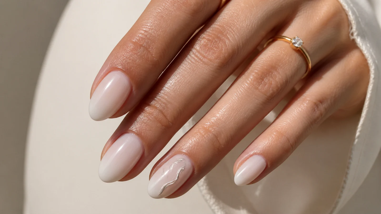 Milky nails with a white chrome swirl accent on the ring finger