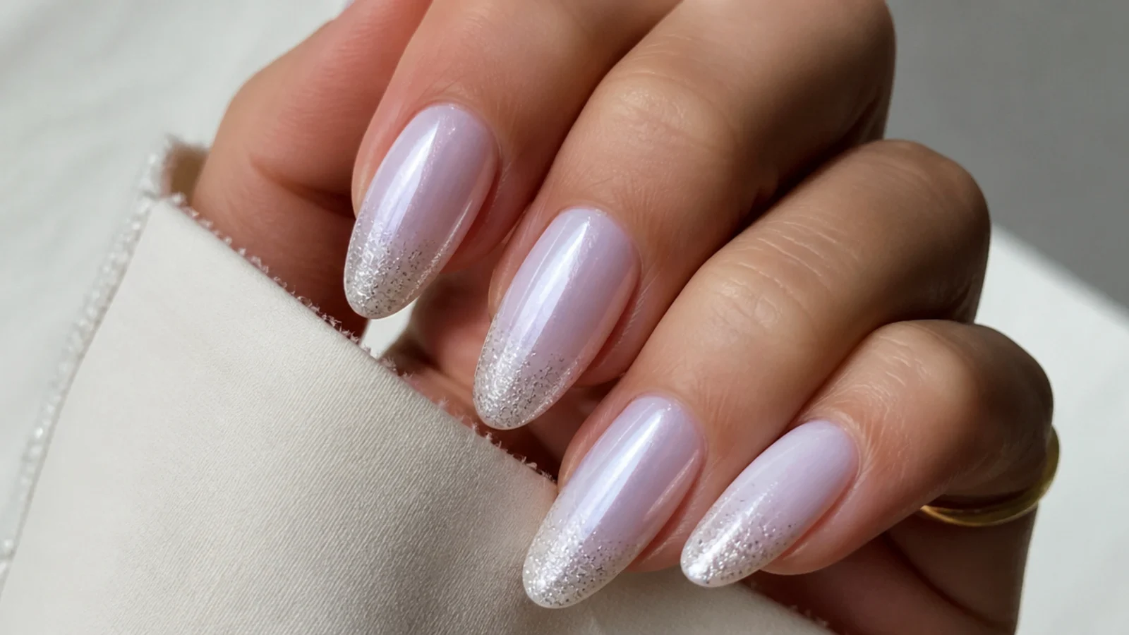 Milky white chrome nails fading into fine silver glitter at the tips