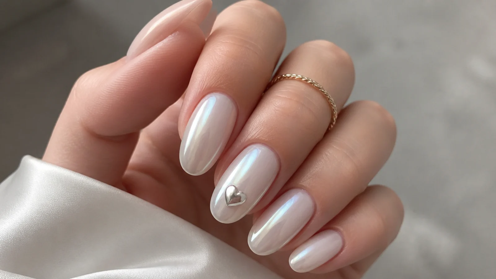 Milky white chrome nails with a small chrome heart on one nail