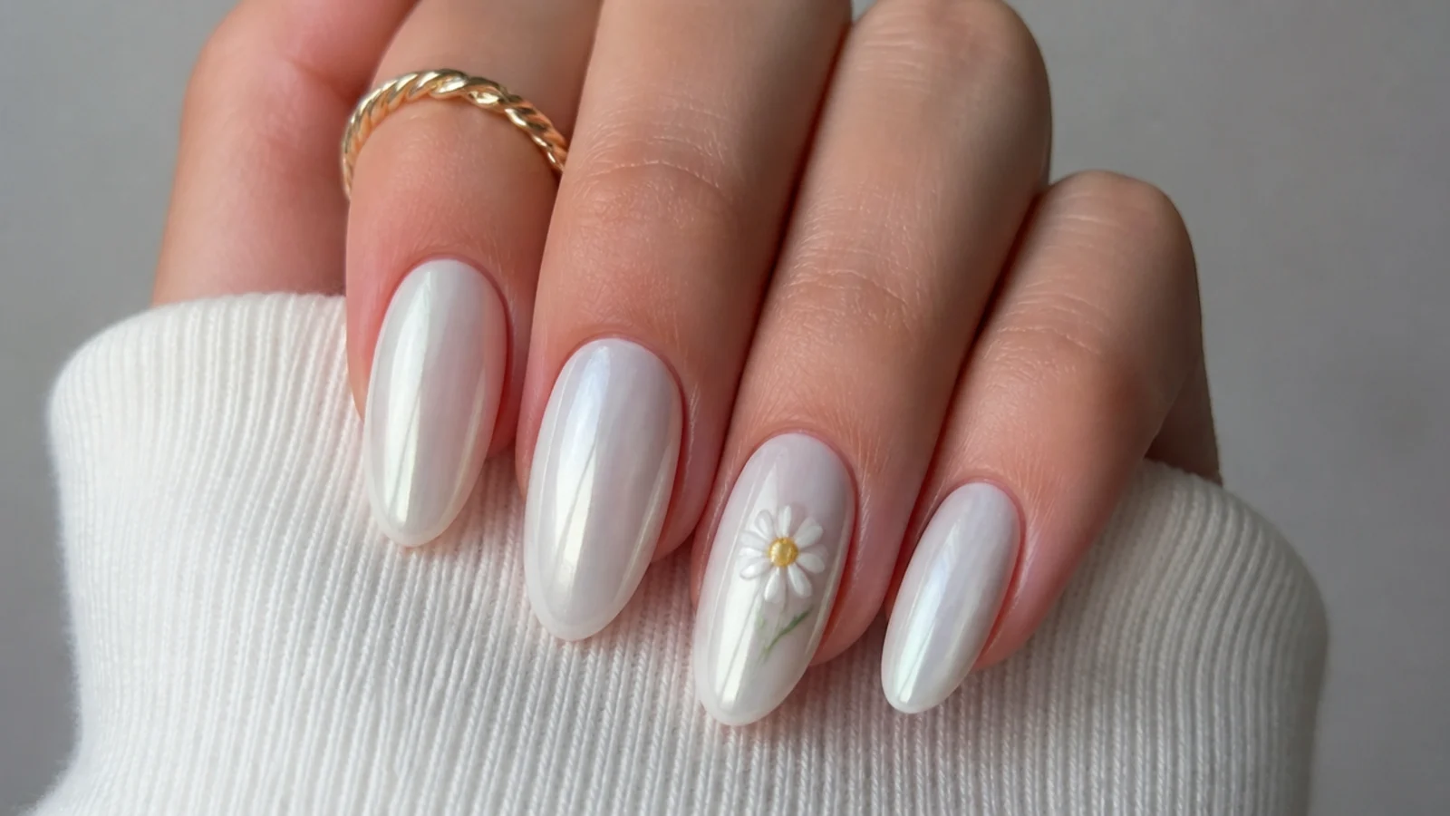 Milky white chrome nails with a small hand-painted daisy accent