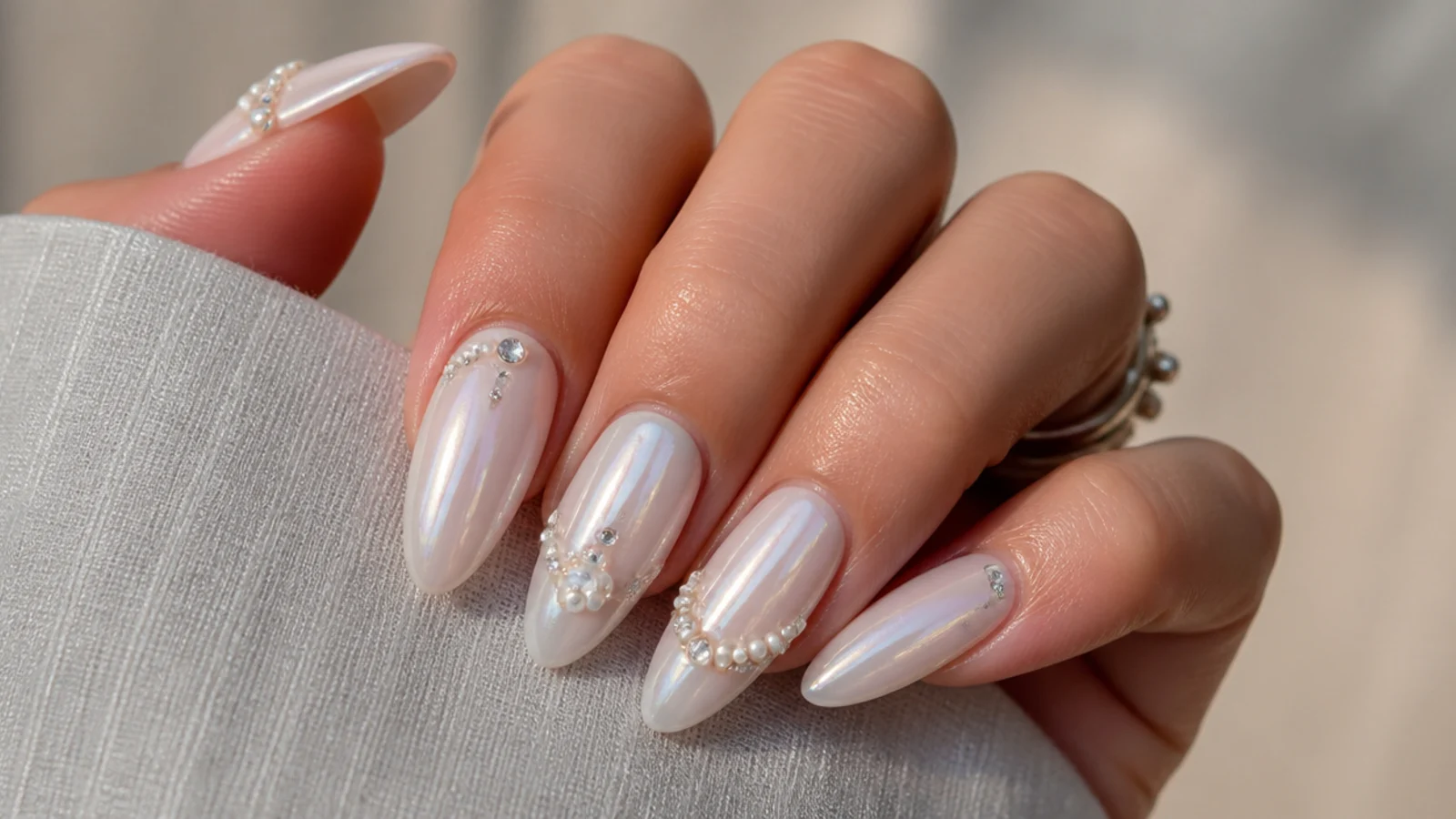 Long milky white chrome nails with crystals and pearl accents