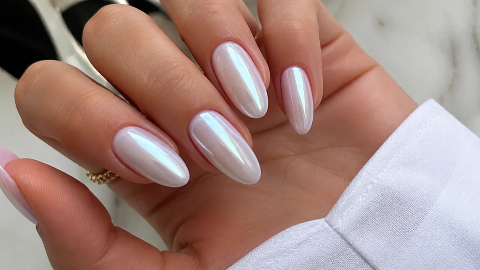 Glossy white chrome nails with a pearl glazed-donut sheen on an almond shape