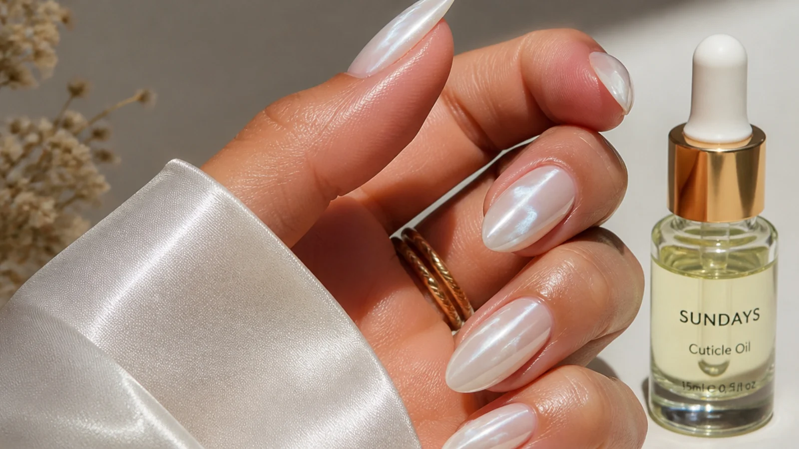 A well-sealed glassy white chrome manicure beside cuticle oil for longevity