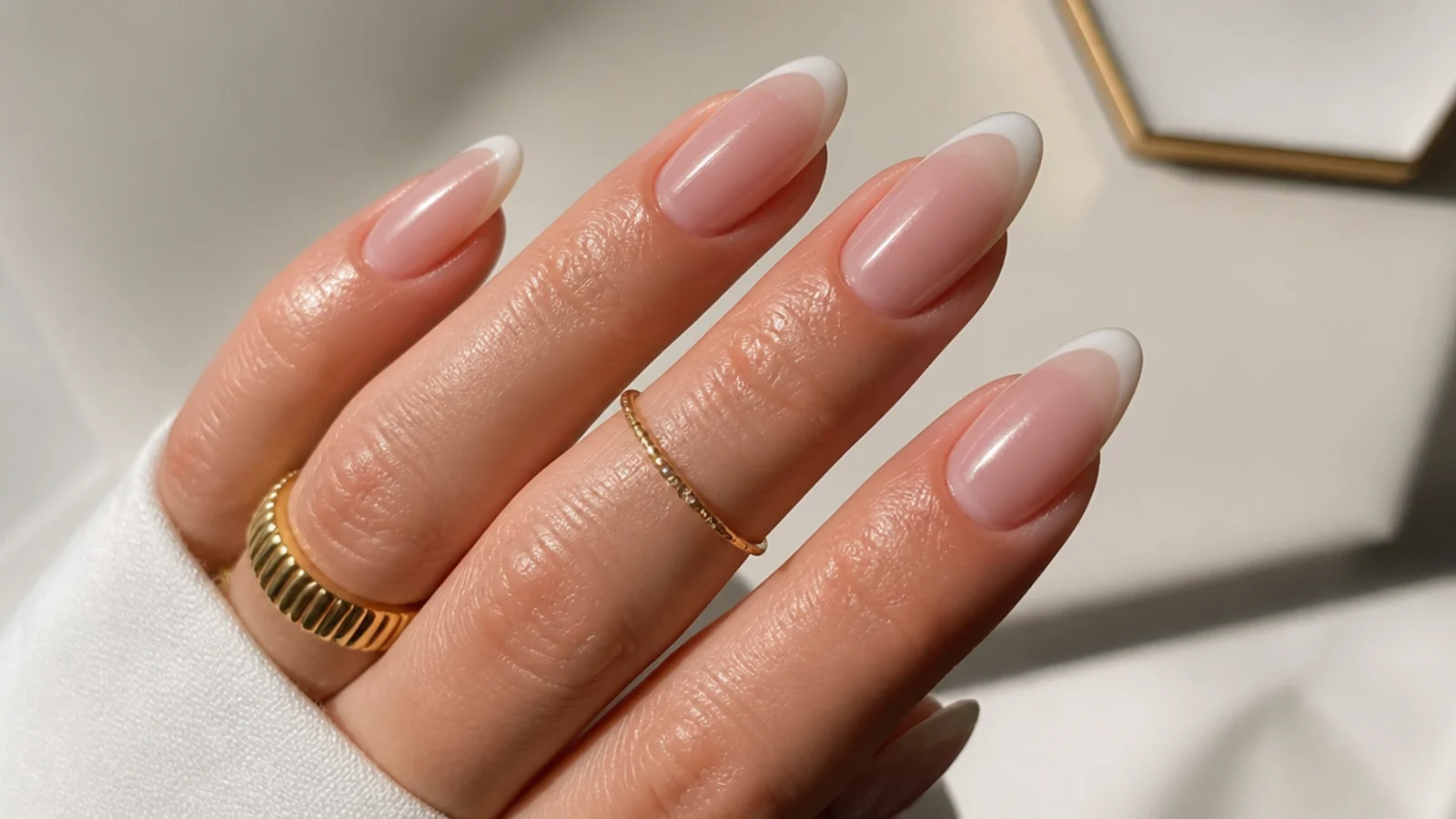 Sheer pink base with a milky white chrome French tip on almond nails