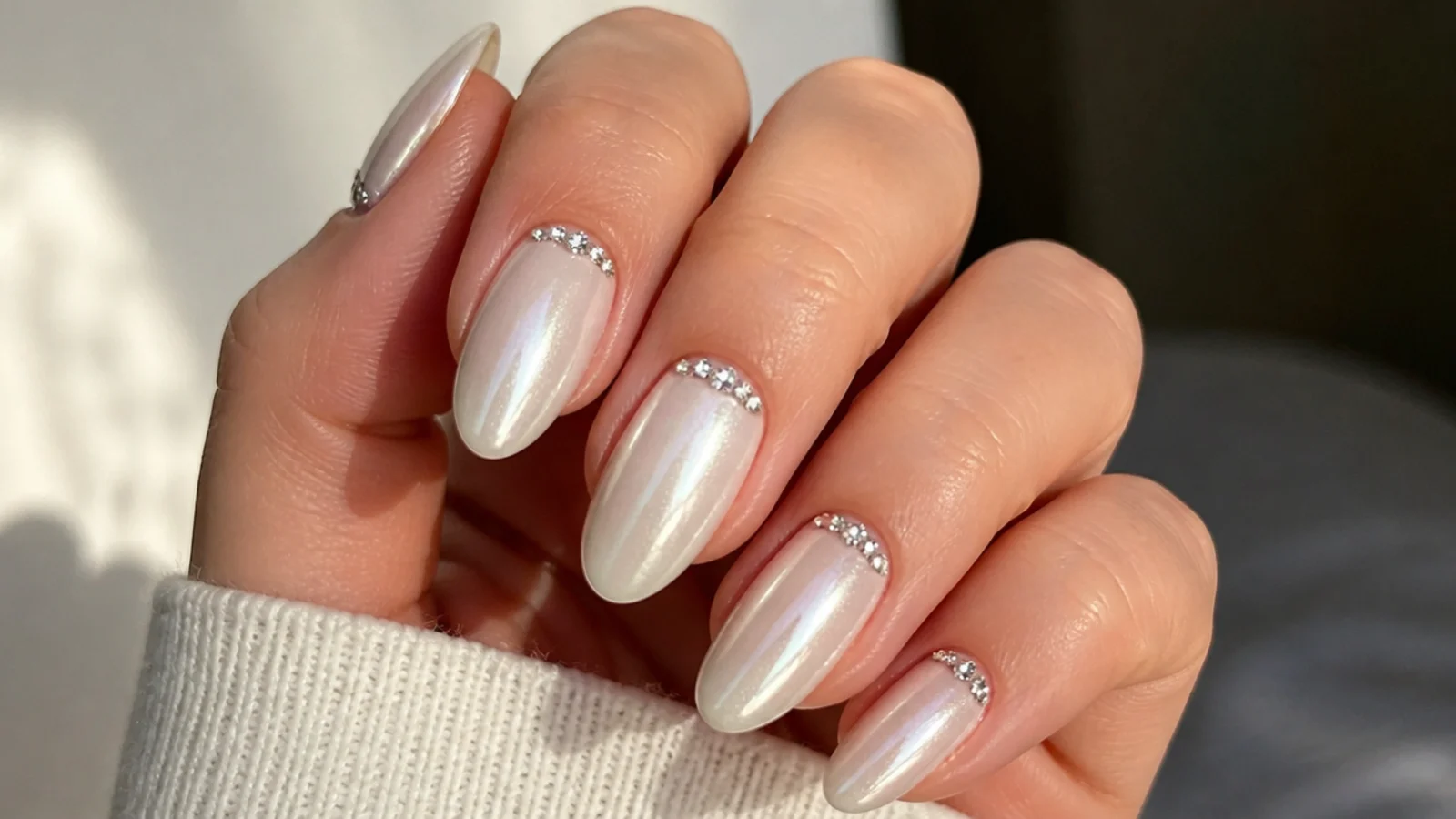 Pearl white chrome nails with tiny crystals set at the cuticle