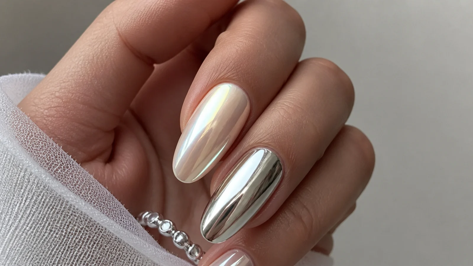 Soft pearl white chrome nail beside a bright mirror silver chrome nail