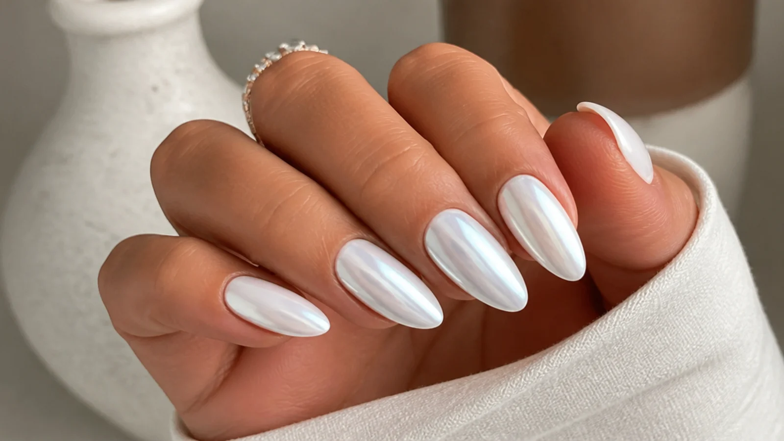 Bridal white chrome nails with a soft pearl glow on a long almond shape