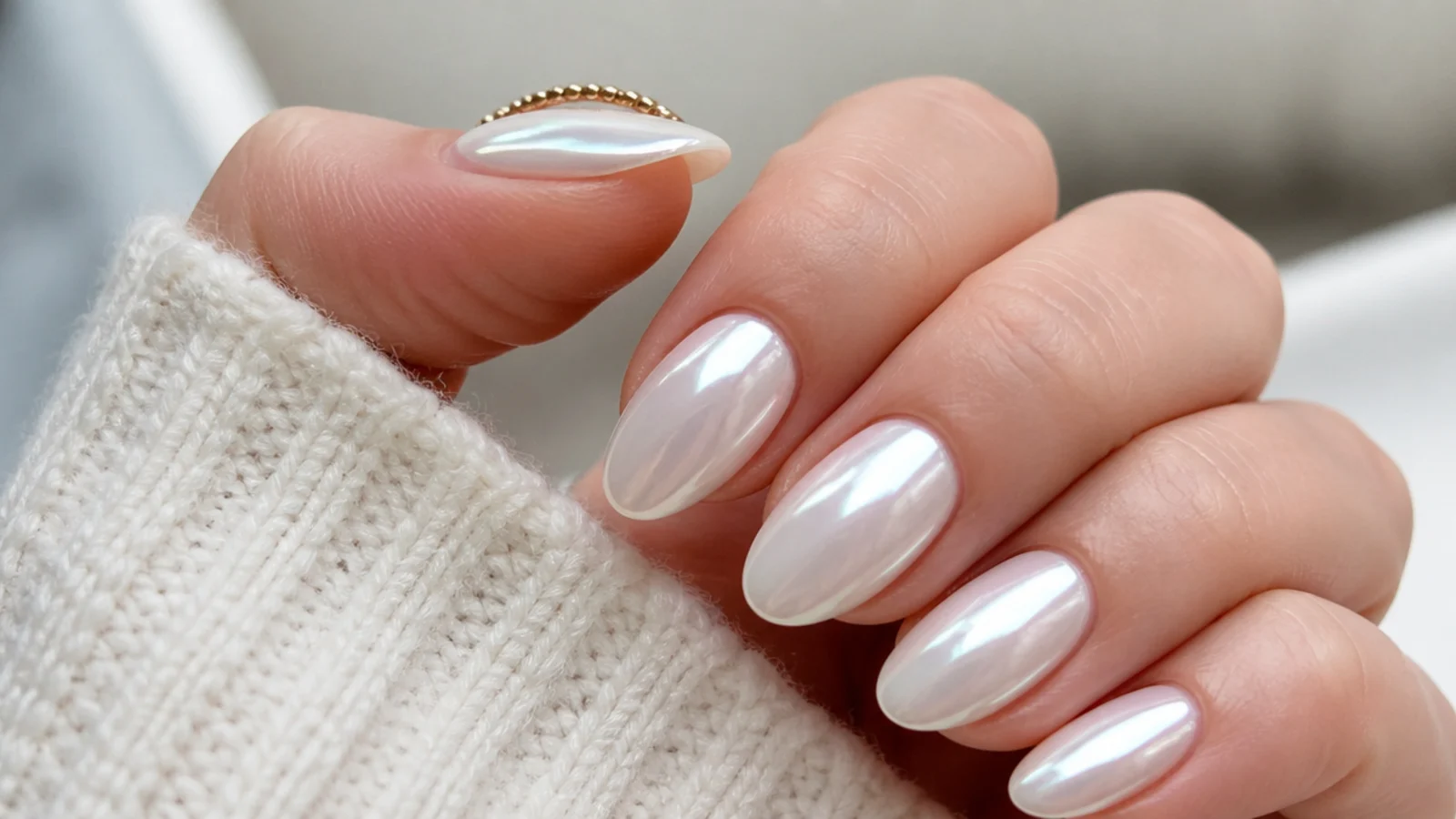 Glassy white chrome nails with a pearl glazed-donut glow on an almond shape