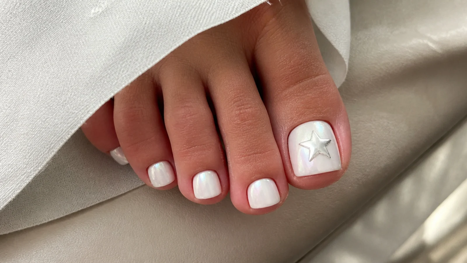 White chrome toe nails with a tiny silver star on the big toe