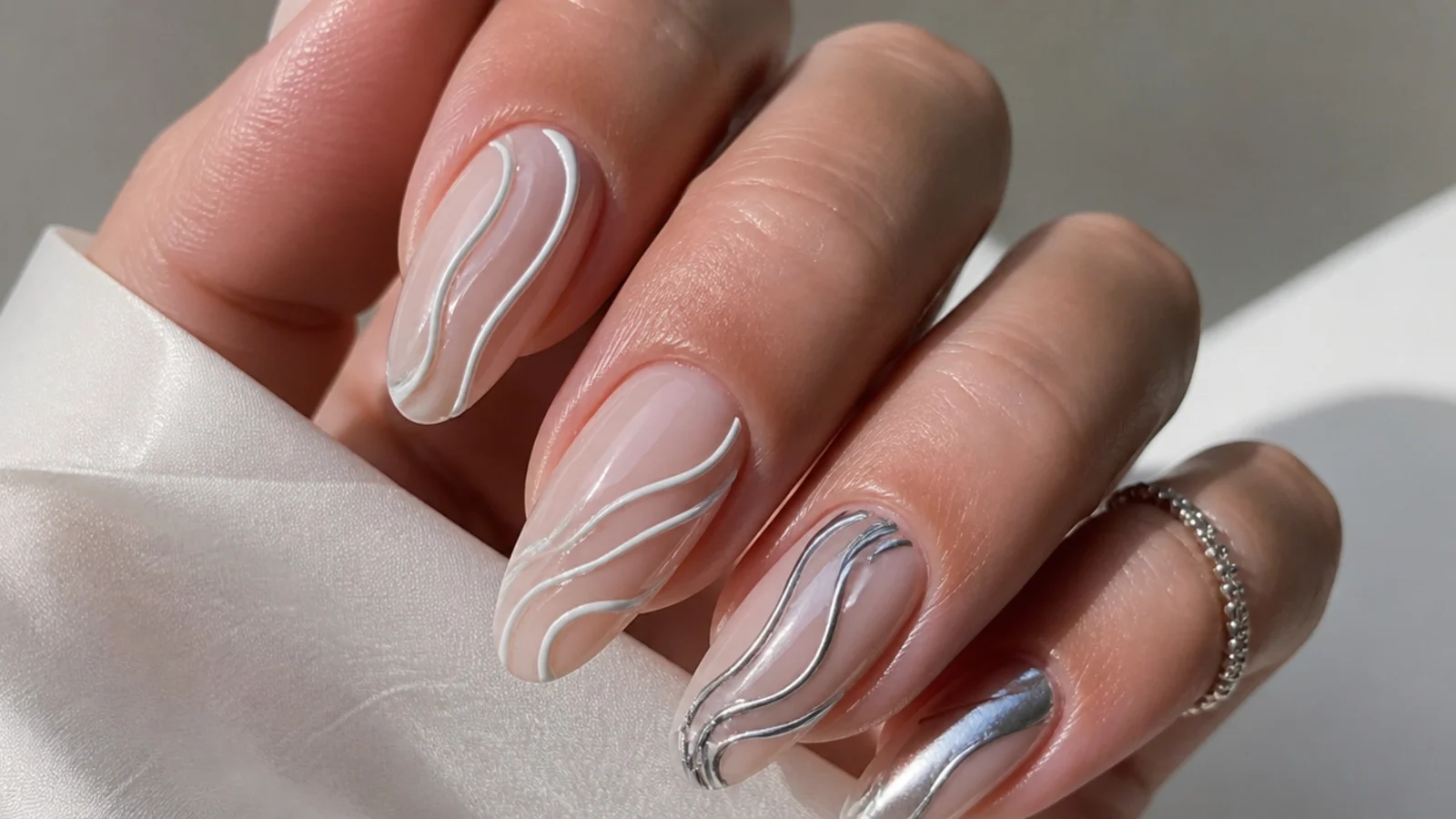 White chrome swirl design beside silver chrome swirl design on a milky base