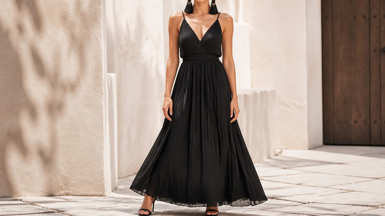 Faceless full-length shot of a flowing black maxi dress with oversized black statement earrings and heels