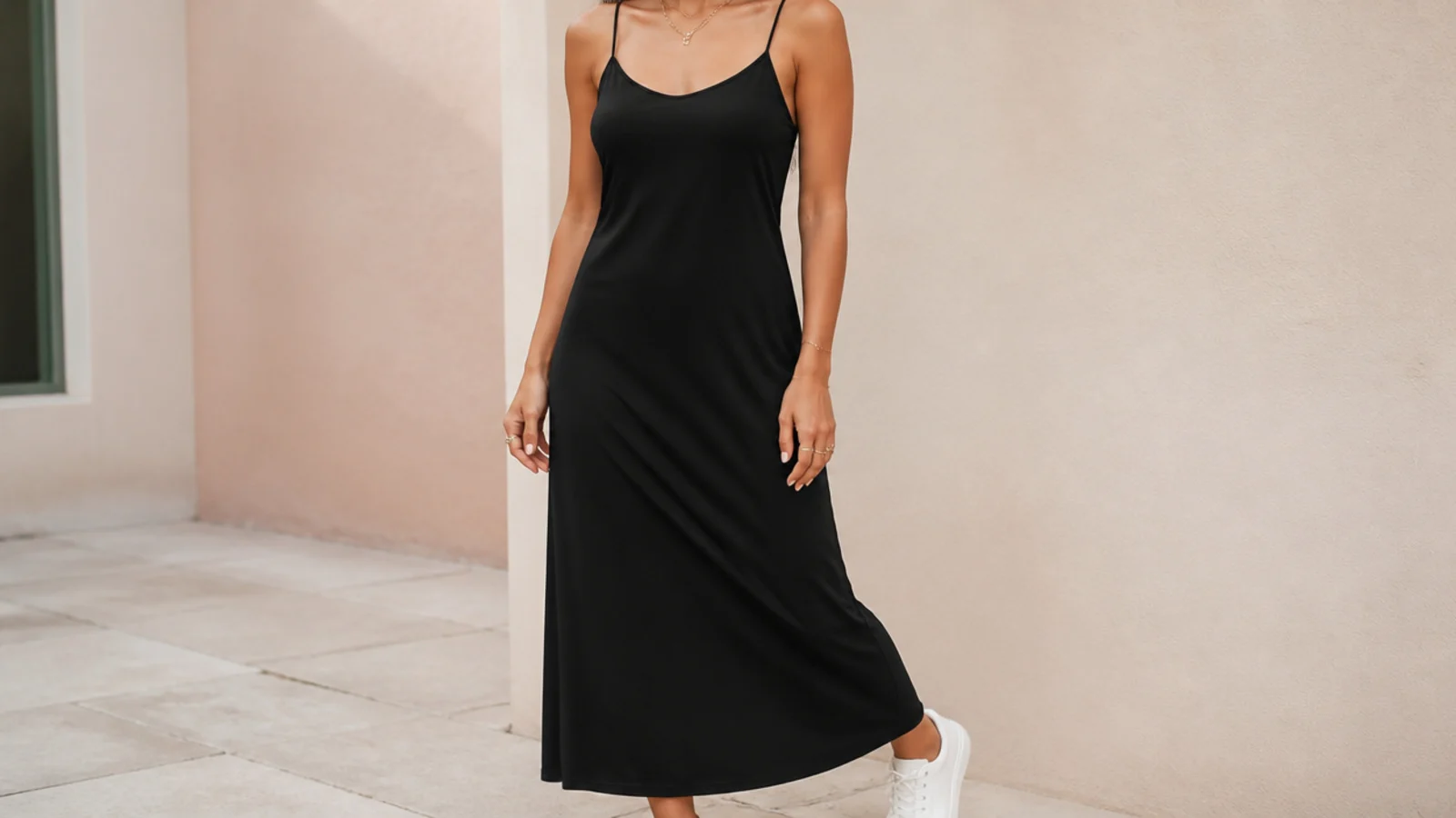 Faceless full-length shot of a black lightweight jersey slip dress with white leather sneakers