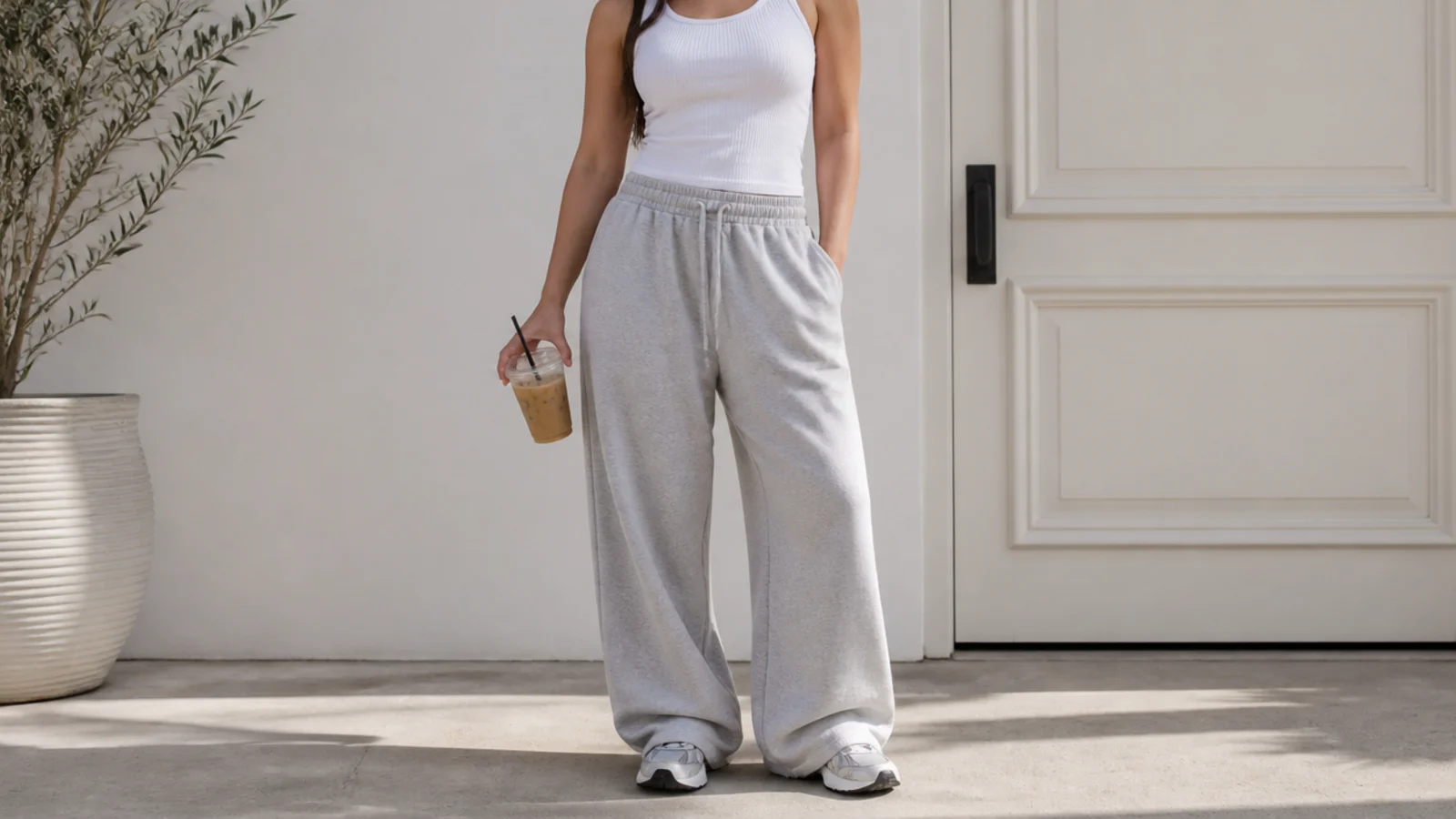 Faceless waist-up shot of a fitted white tank tucked into baggy gray sweatpants at the waist