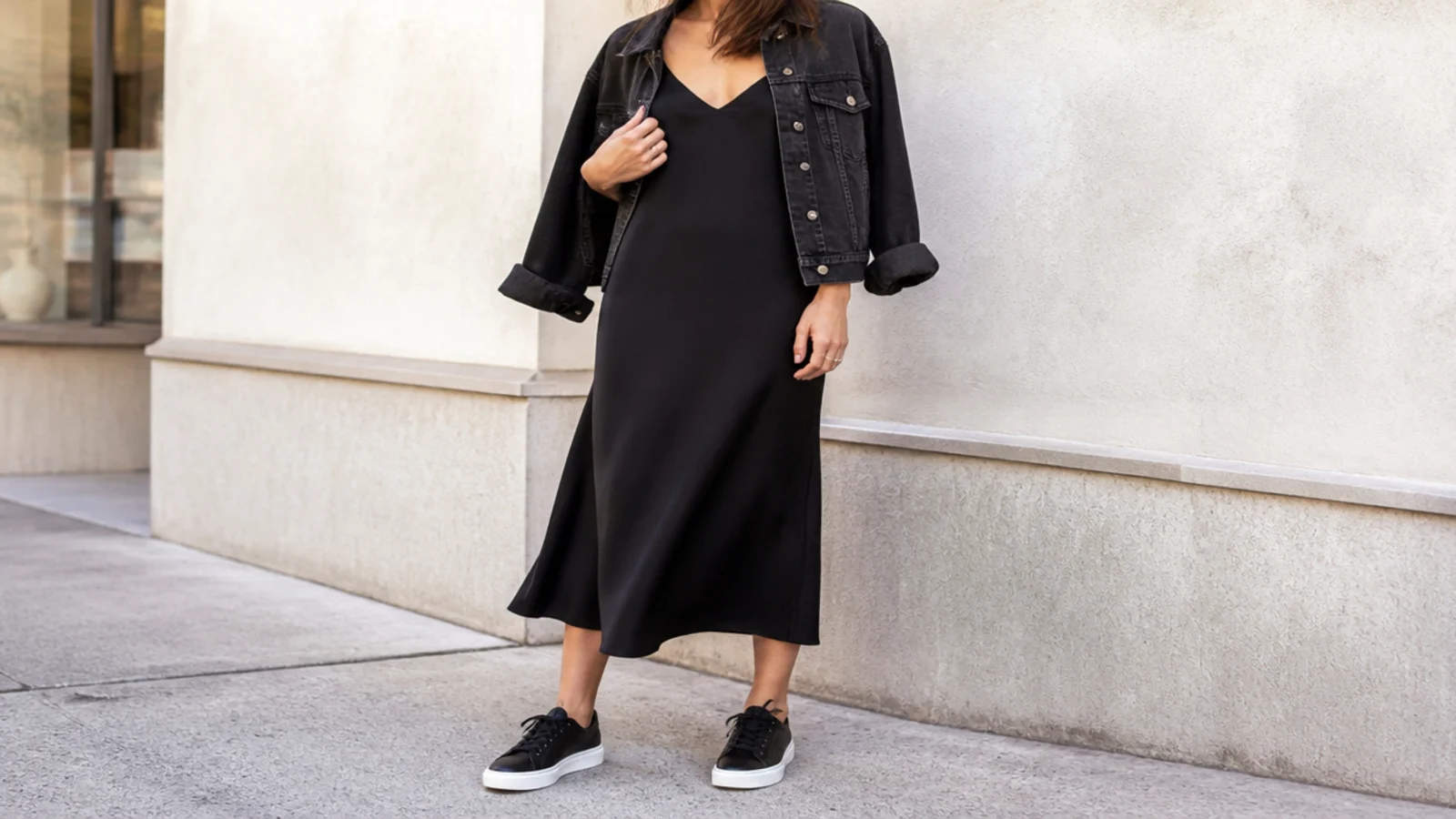 Faceless spring outfit with a black slip dress under a black denim jacket and black leather sneakers