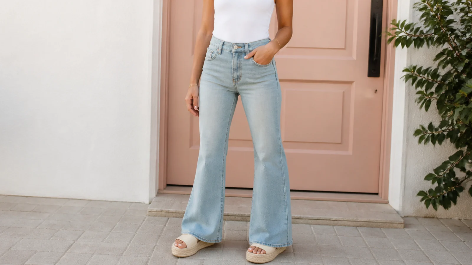 Faceless outfit with high-rise flare jeans, a fitted tucked top and platform sandals