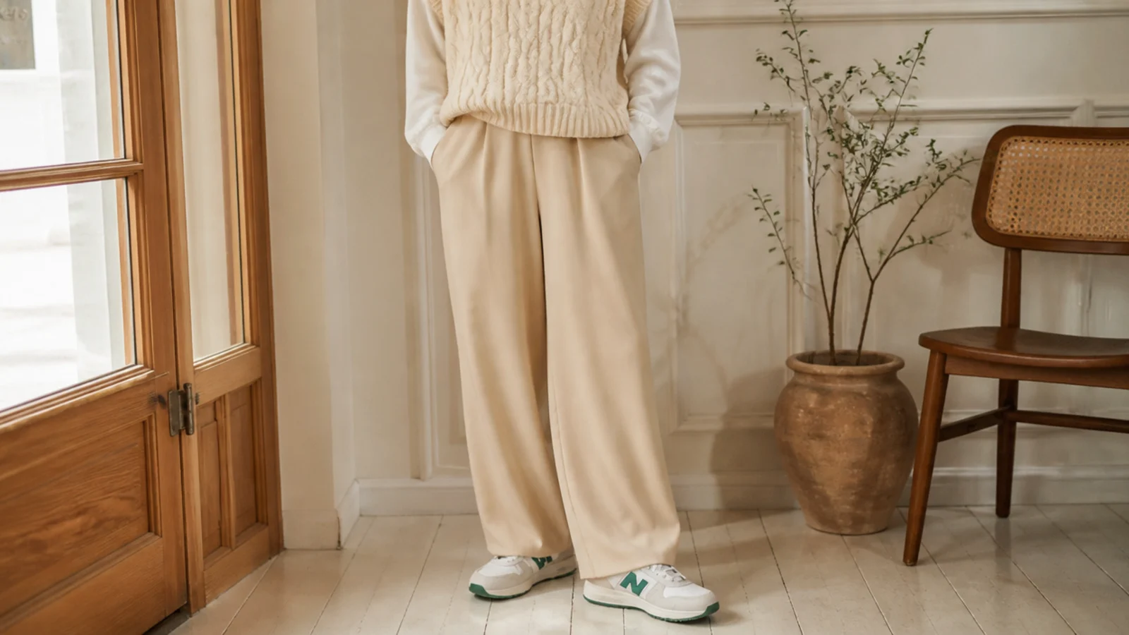 Faceless outfit with retro New Balance 327 sneakers in cream and green, wide-leg trousers and a knit vest