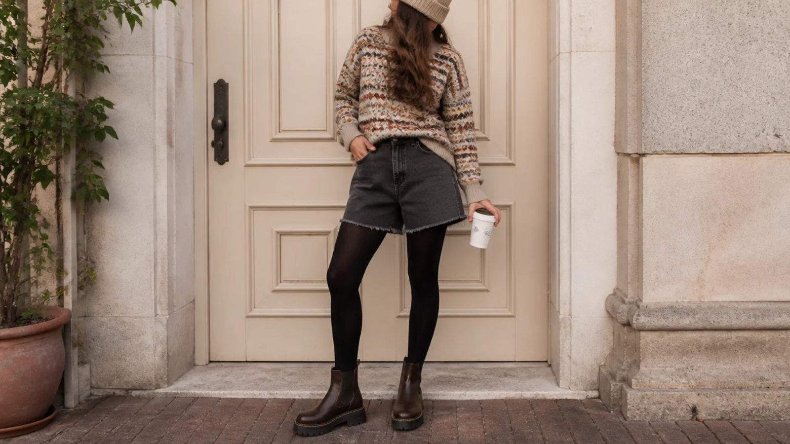 Faceless cozy fall outfit with dark jorts, a patterned Fair Isle sweater, opaque tights, lug-sole boots and a beanie