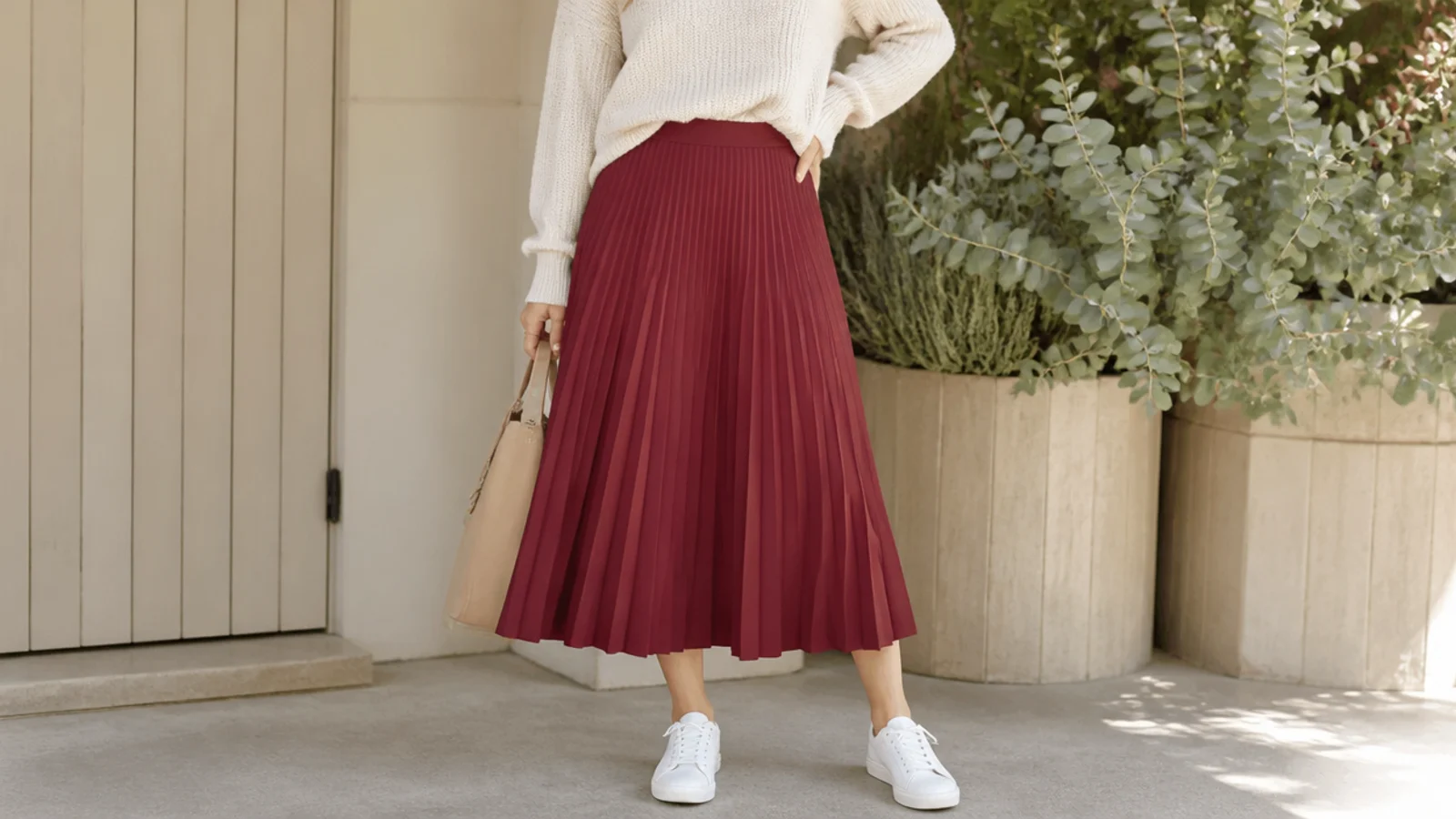 Faceless fall outfit with white sneakers, a burgundy pleated midi skirt and a tucked cream knit