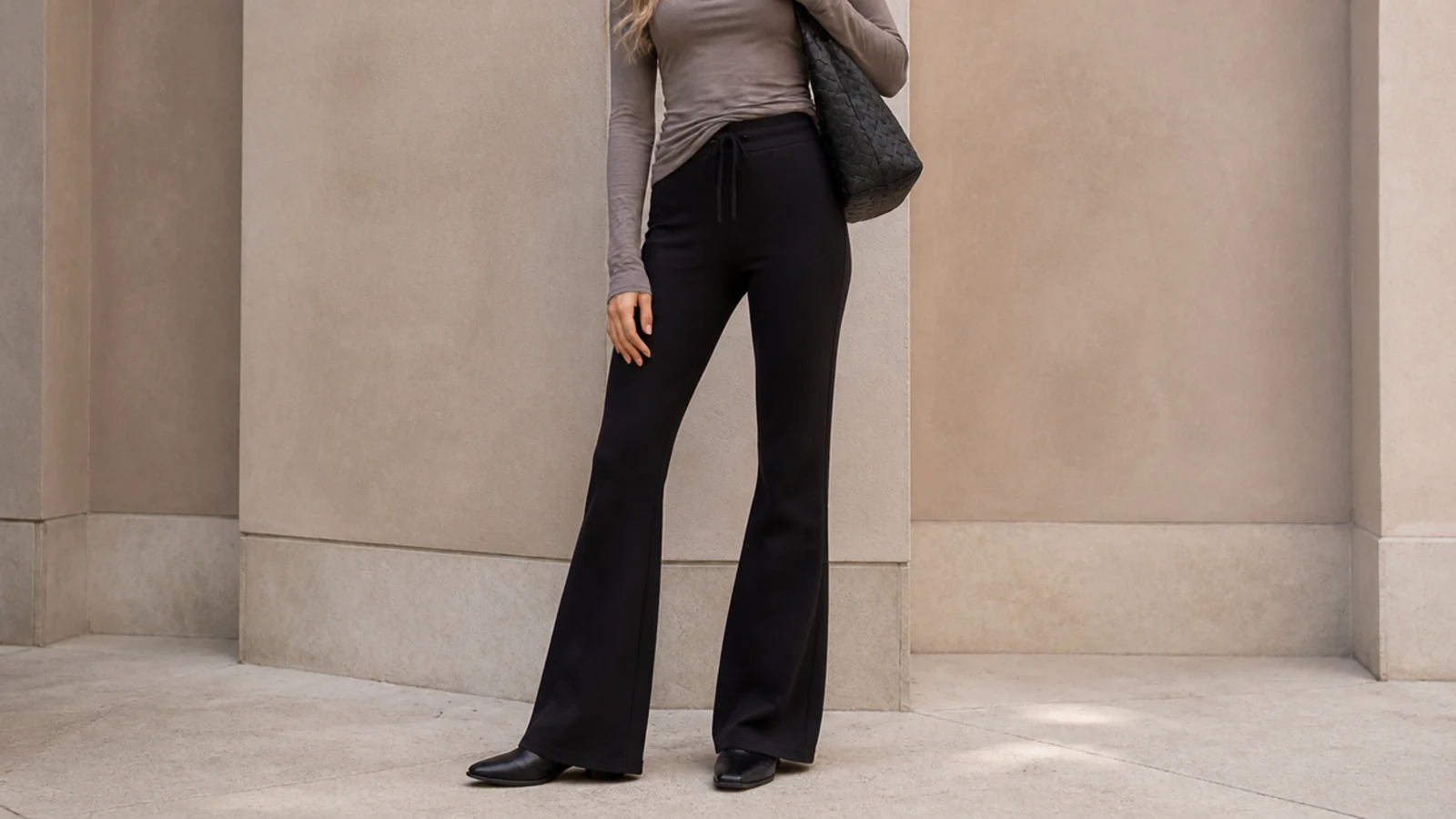 Faceless outfit with black flare sweatpants and a low-heeled black ankle boot hidden under the flared hem