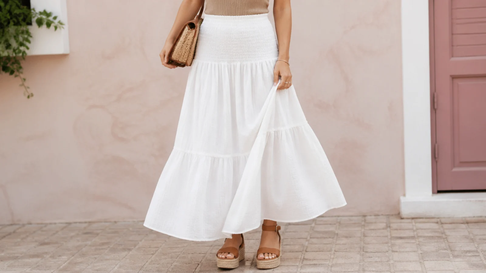 Faceless waist-down shot of tan platform sandals lifting the hem of a white maxi skirt off the ground