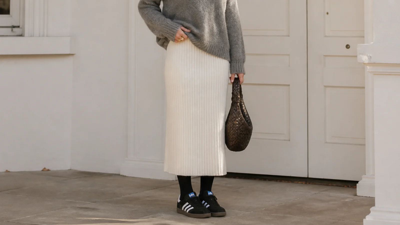 Faceless full-length shot of a ribbed knit midi skirt with black and white Adidas Samba sneakers and opaque tights