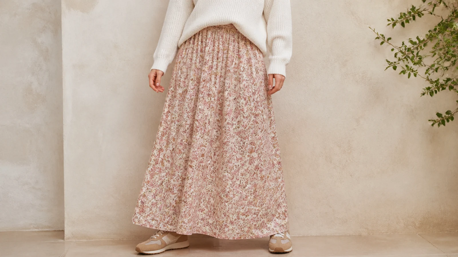 Faceless full-length shot of a flowing floral maxi skirt with tan suede and mesh retro running sneakers peeking at the hem