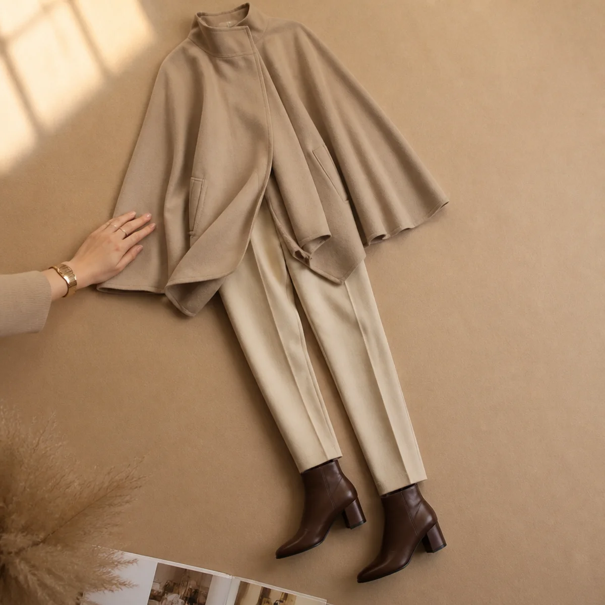 Faceless full-length shot of a cape-style coat over trousers with ankle boots in the rain