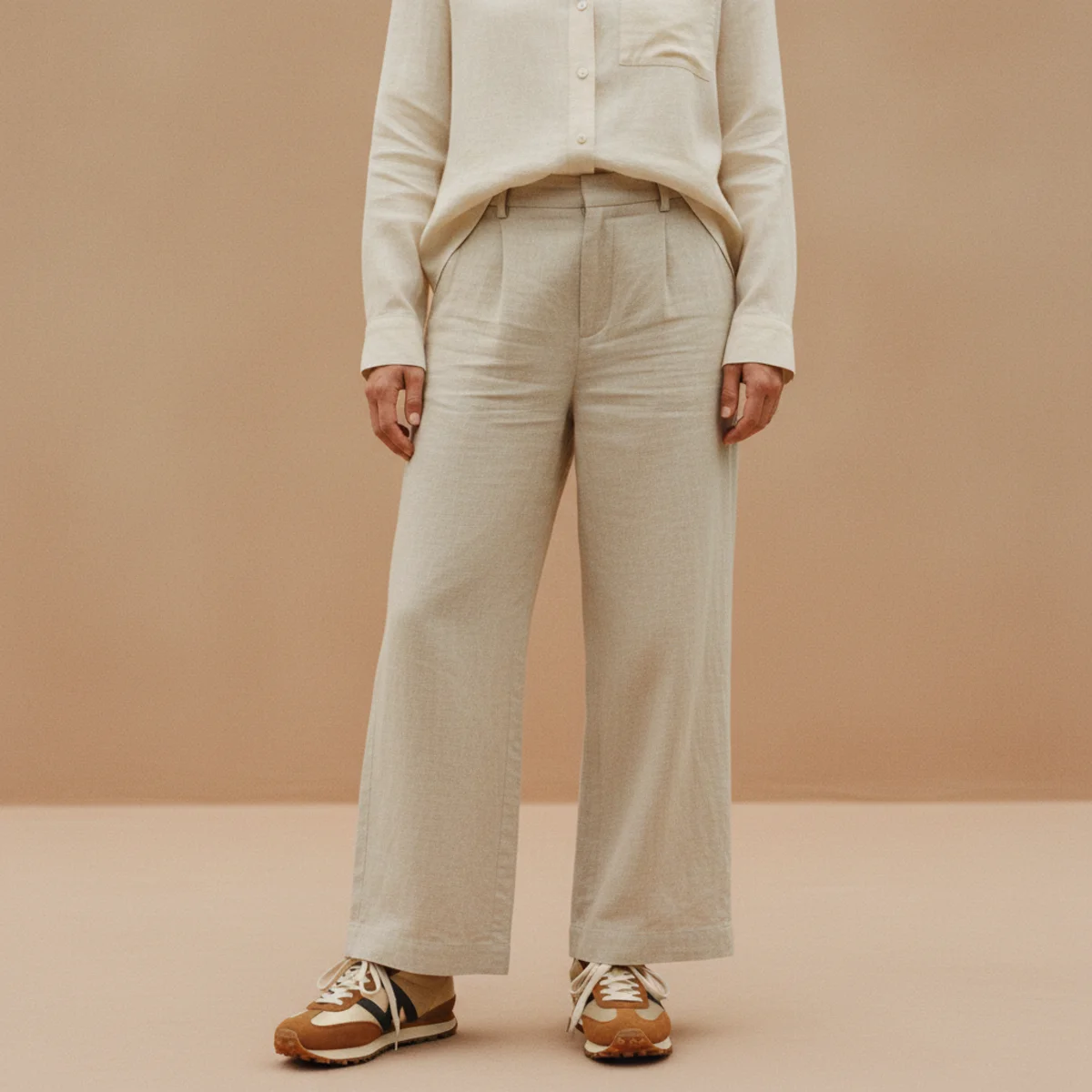 Faceless waist-down shot of retro gum-sole sneakers with wide-leg natural linen trousers and a boxy white shirt