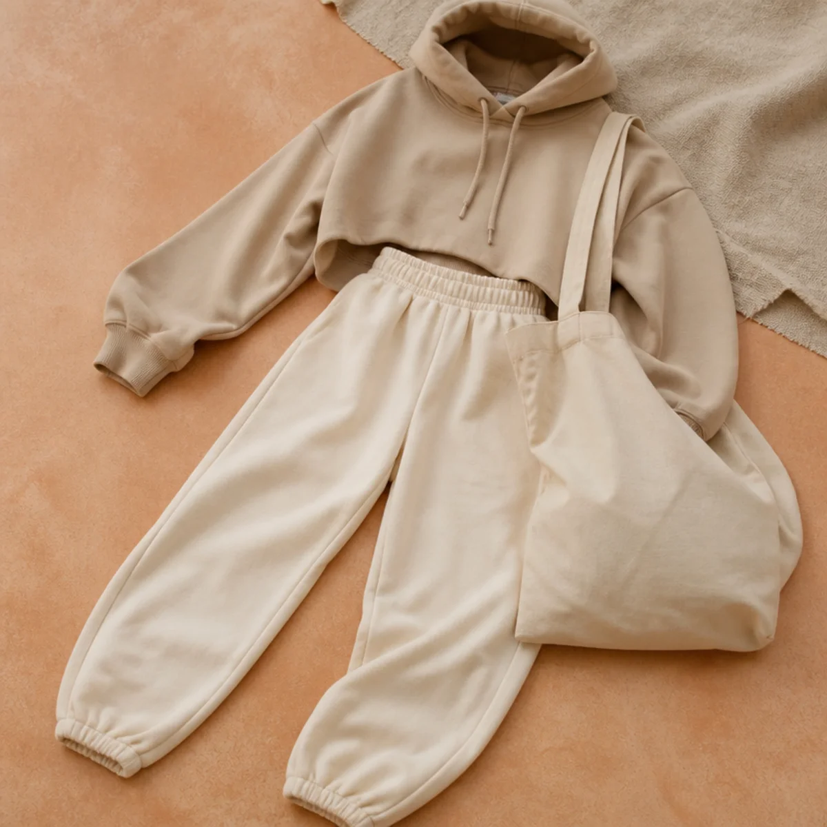 Faceless waist-down shot of high-waisted joggers with a cropped hoodie and a canvas tote