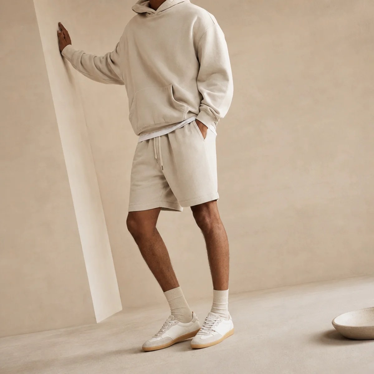 Faceless waist-down shot of sweat shorts with an oversized hoodie and trainers for warm-weather campus days