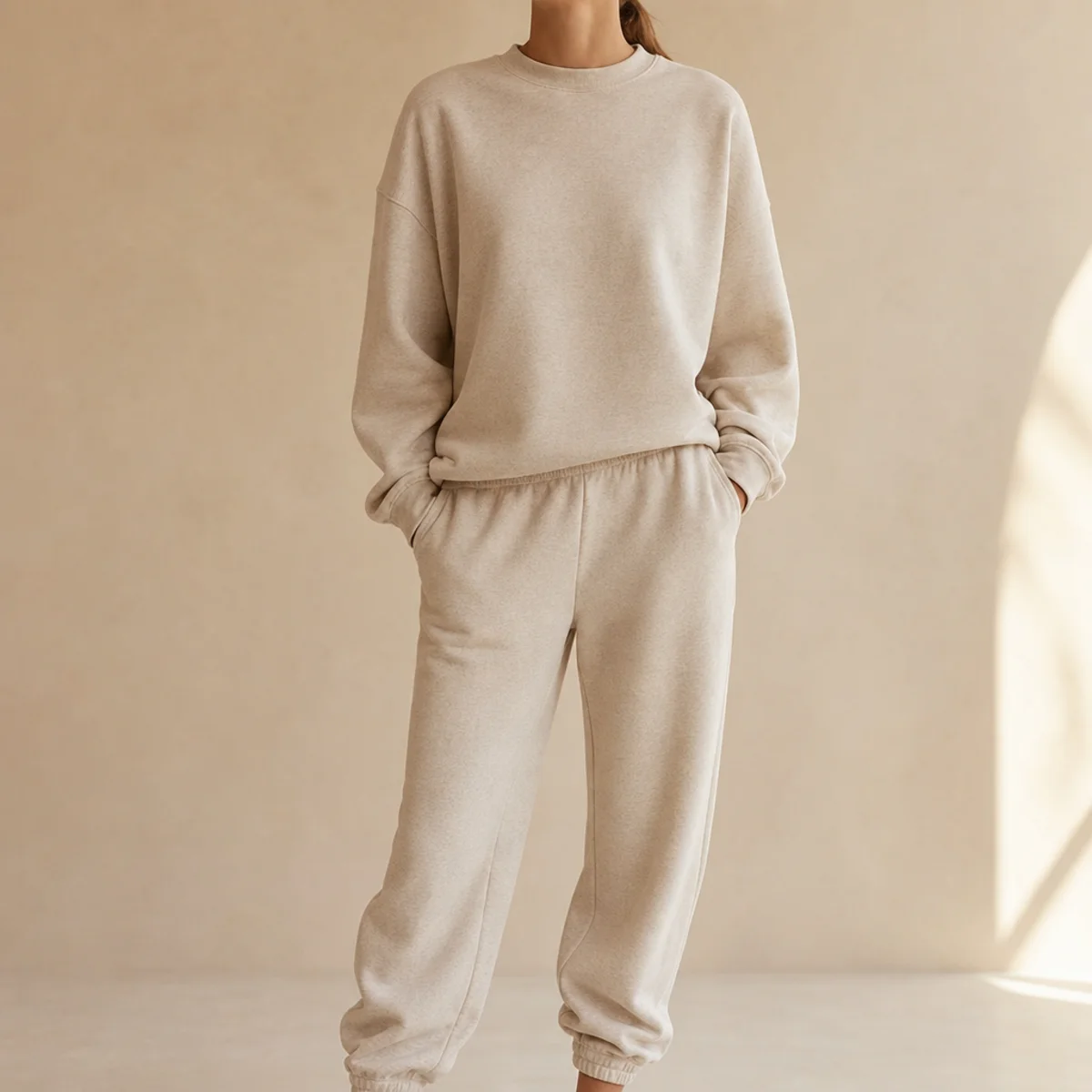 Faceless waist-up shot of a tonal matching sweatshirt and sweatpants co-ord in soft oatmeal