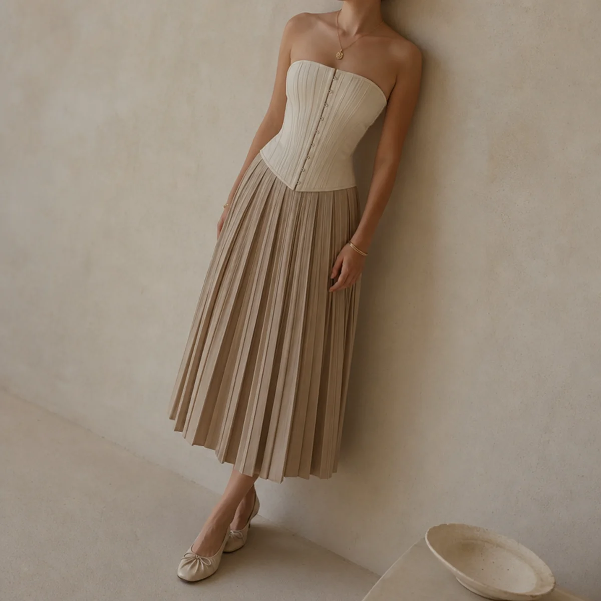 Faceless full-length shot of a corset top with a pleated midi skirt and ballet flats