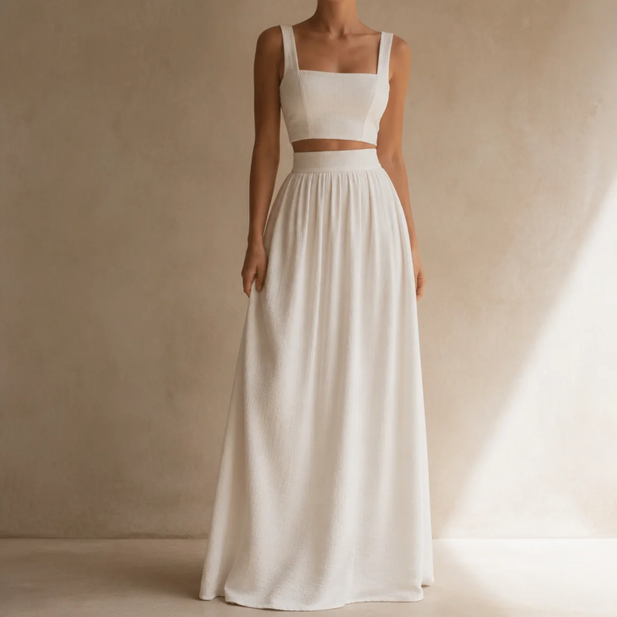 Faceless waist-up shot of a high-waisted white maxi skirt with a fitted crop top