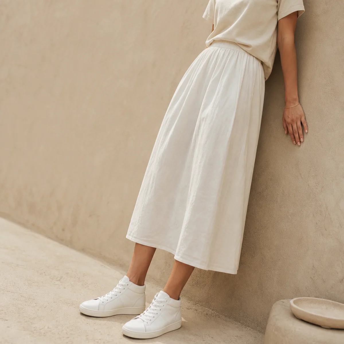 Faceless full-length shot of a white midi skirt with a tee and white sneakers