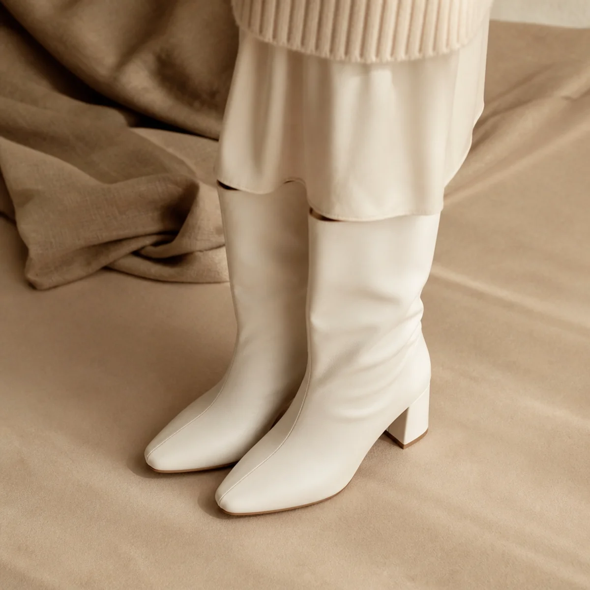 Faceless full-length shot of a white midi skirt with a knit and tall boots