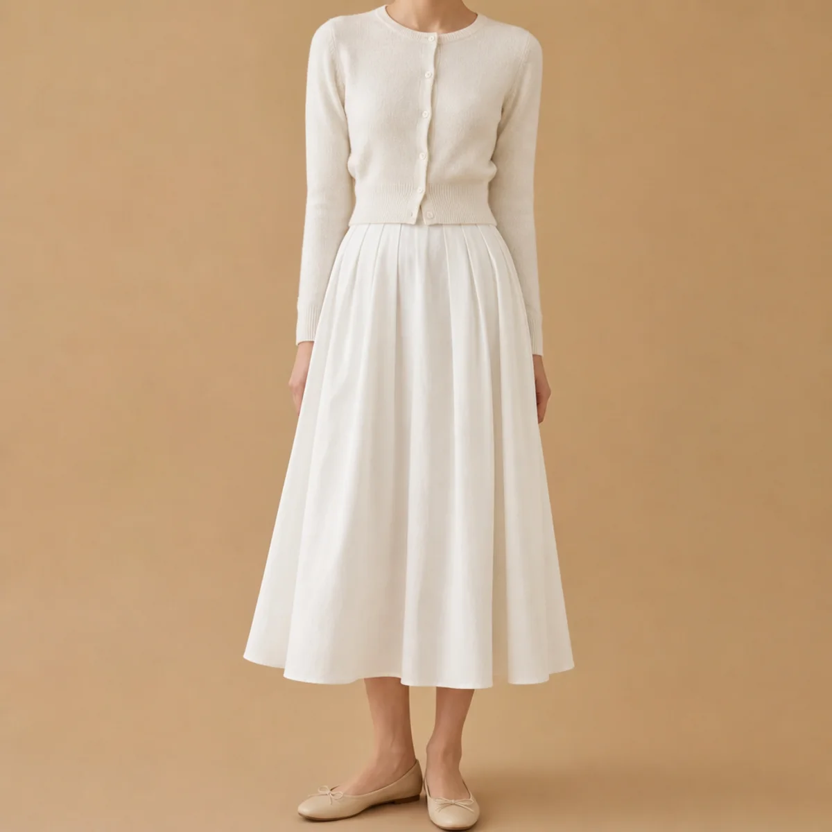 Faceless waist-up shot of a white midi skirt with a cropped cardigan and flats