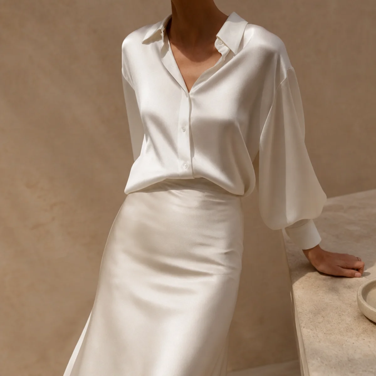 Faceless waist-up shot of a white satin skirt with a crisp button-down half-tucked