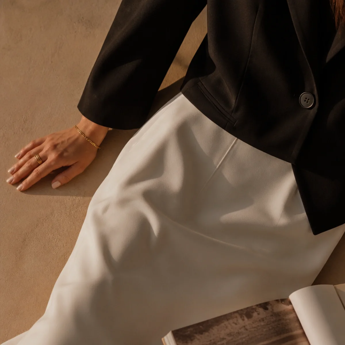 Faceless waist-up shot of a white skirt with a black blazer and heels