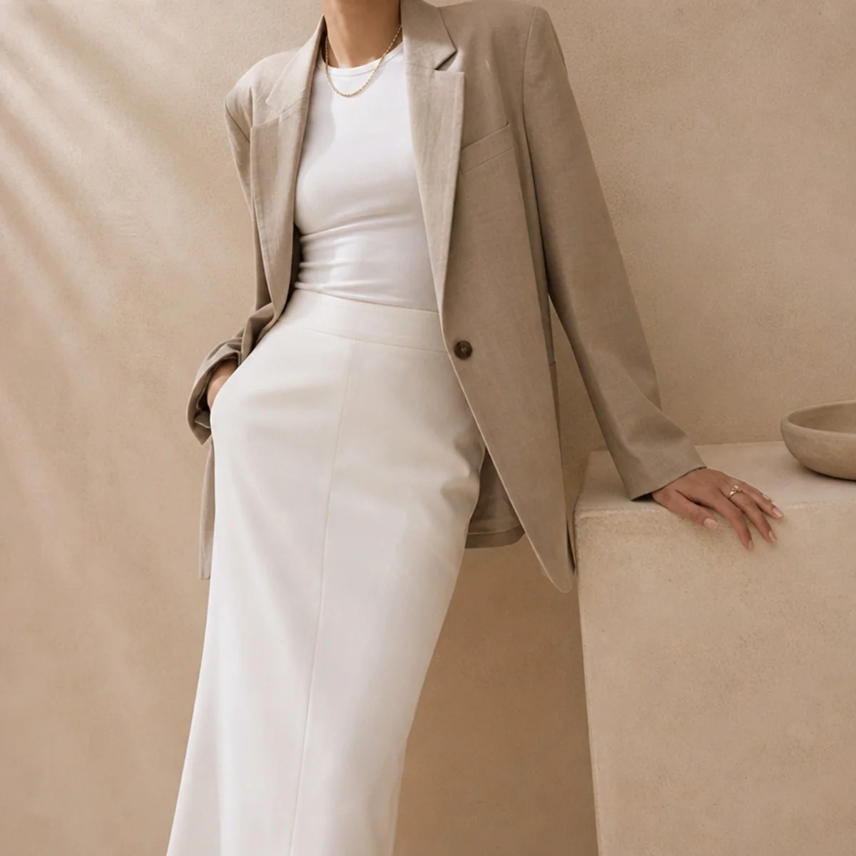 Faceless waist-up shot of a white skirt with a fitted tee under a blazer