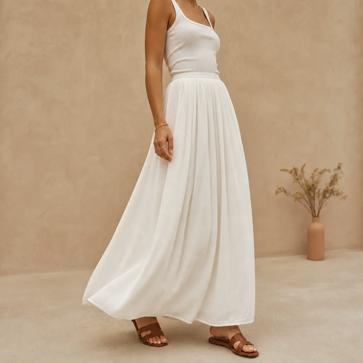 Faceless full-length shot of a flowing white maxi skirt with a fitted tank and sandals