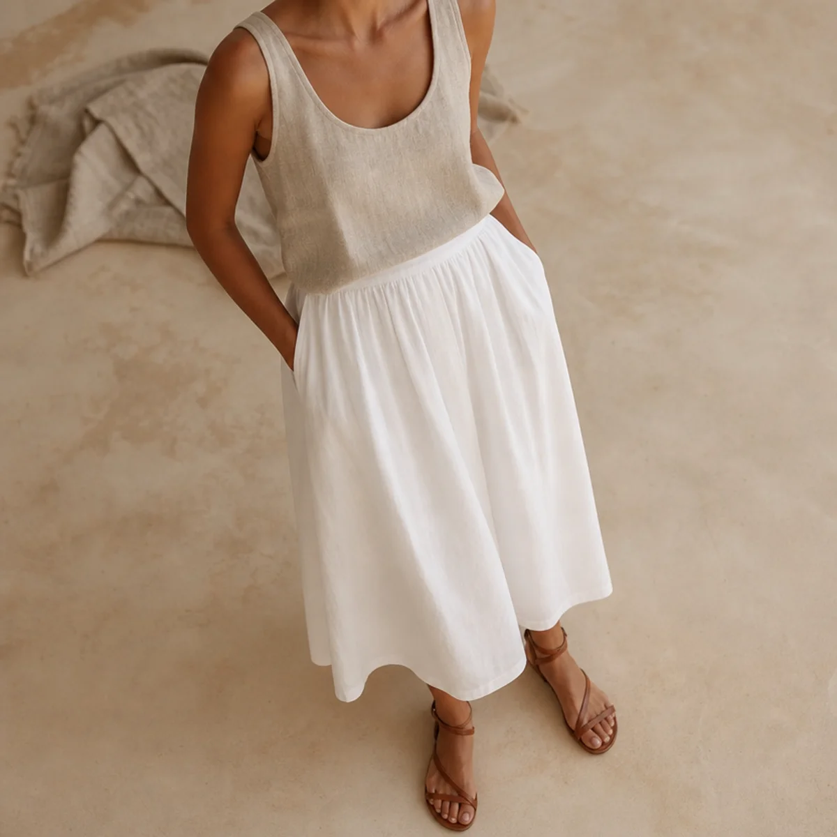 Faceless full-length shot of a white skirt with a linen tank and flat sandals