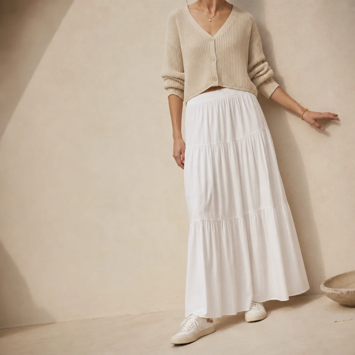 Faceless waist-up shot of a white skirt with a cropped cardigan and sneakers